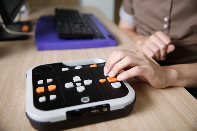 Blind person using audio book player for visually impaired, listening to audio book on his computer. Blindness aid, visual impairment, independent life concept.